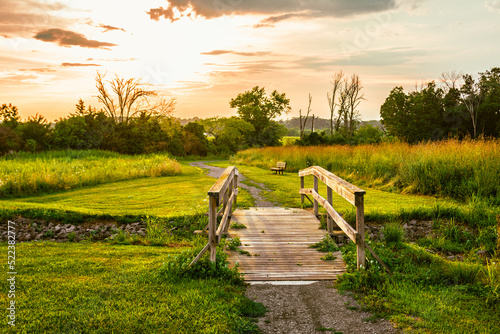 The pathway with the wooden bridge illuminated by the sunset sky