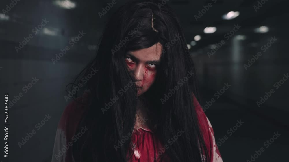 Happy halloween day concept. Screaming zombie female face with blood grabs her head to twist it off, Horror bloodthirsty woman ghost or zombie she is horror scary with breaks her neck at dark night Happy halloween day concept. Screaming zombie female face with blood grabs her head to twist it off, Horror bloodthirsty woman ghost or zombie she is horror scary with breaks her neck at dark night