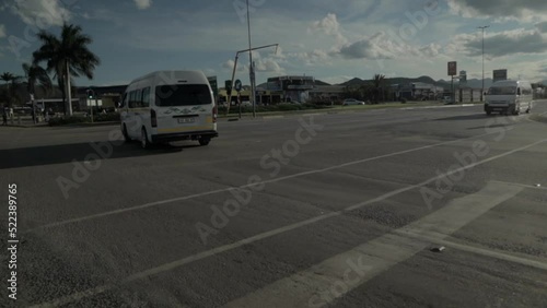 A static shot of a white car which is being used as public transport running on a street