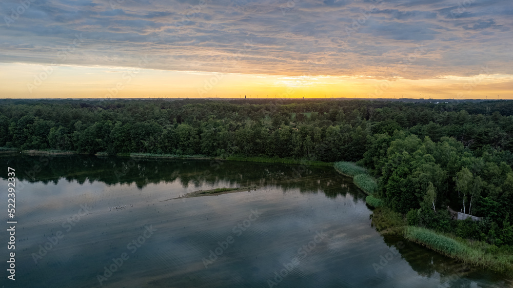 Aerial view, shot by a drone of a sunset at coast of the lake. Nature landscape. Nature in northern Europe. reflection, blue sky and yellow sunlight. landscape during sunset. High quality photo