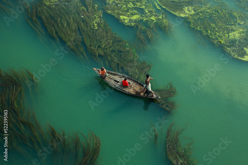 Fishermen are seen floating on top of algae as they search for potential catch in the sharp green waters of a river. The Sirajganj spot in Bangladesh is a popular place.