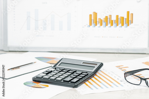 Finance and business concept. calculator on financial graphs on office desk, laptop and glasses. Accounting budgeting or market analysis. Web banner with copy space