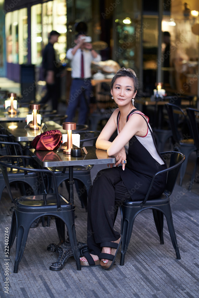 Asian beauty sitting at outdoor table of a bar waiting for service