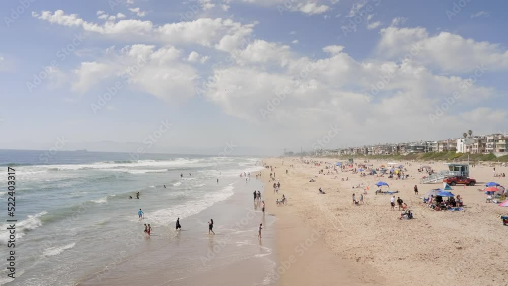 An aerial view of sandy beach with tourists swimming in beautiful clear sea water. Few tourists are seen resting while sitting on the beach An aerial view of sandy beach with tourists swimming in beautiful clear sea water. Few tourists are seen resting while sitting on the beach