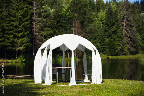 Small wedding tent with white curtains near the lake