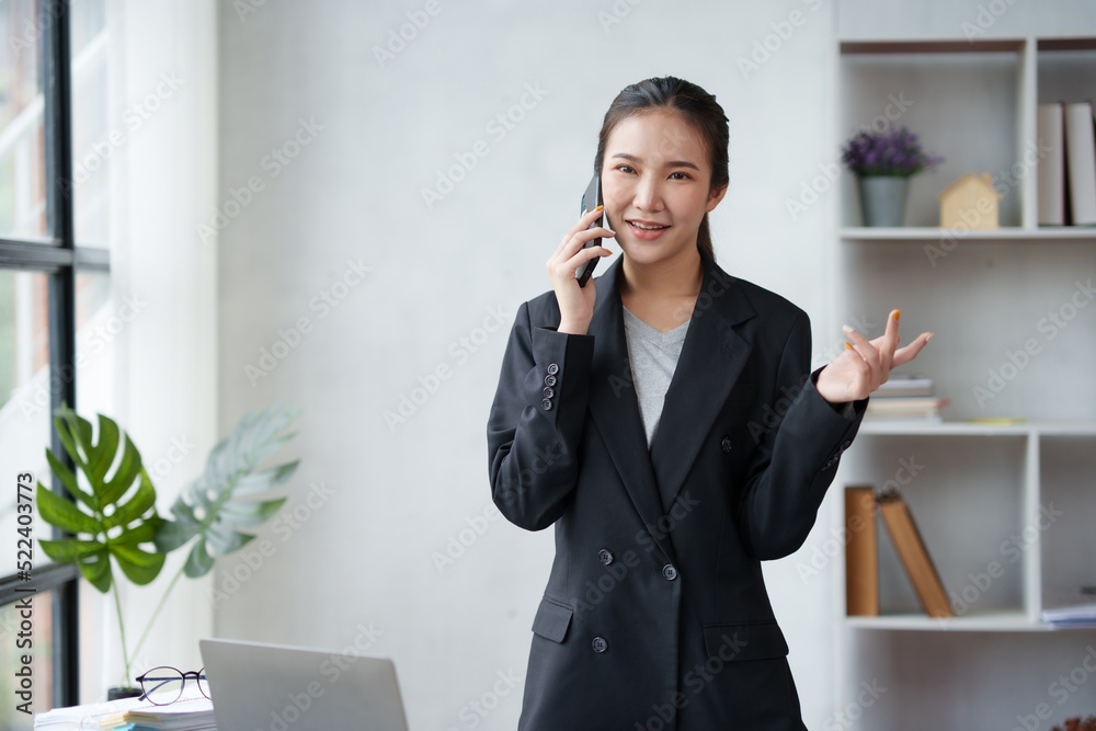 Beautiful Asian business woman is standing and chatting with a customer and explaining the job in detail to the customer in the office. Beautiful Asian business woman is standing and chatting with a customer and explaining the job in detail to the customer in the office.