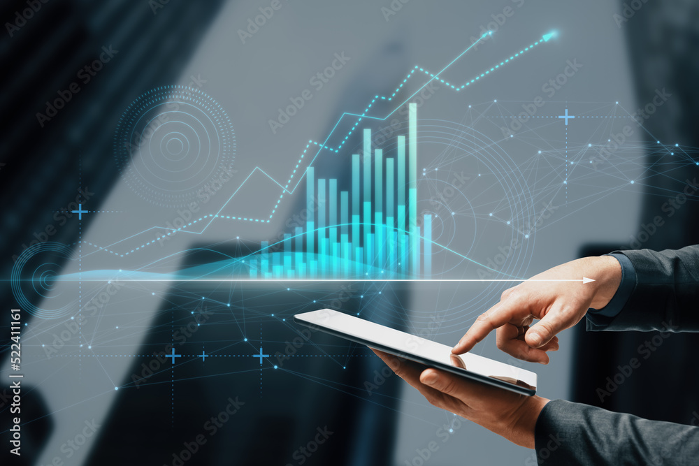 Close up of businessman hand pointing at tablet with abstract glowing polygonal business graph hologram with growing arrow on blurry city background. Financial growth, market and trade concept. Close up of businessman hand pointing at tablet with abstract glowing polygonal business graph hologram with growing arrow on blurry city background. Financial growth, market and trade concept.