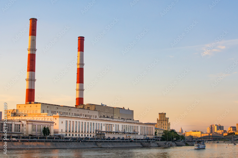 Moscow, Russia - August 2, 2022 : thermal power plant in Moscow on the waterfront and a motor ship taking a boat trip