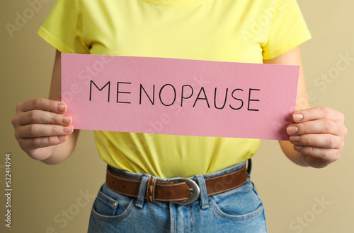 Woman holding card with word Menopause on beige background, closeup © New Africa