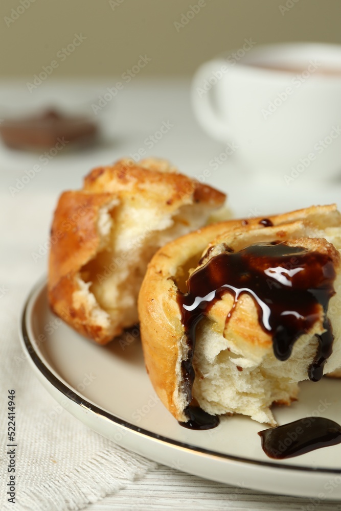 Delicious bun with chocolate sauce on white table, closeup Delicious bun with chocolate sauce on white table, closeup