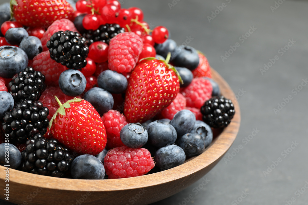 Mix of different fresh berries in bowl on grey table, closeup Mix of different fresh berries in bowl on grey table, closeup