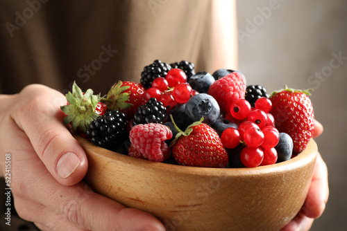 Woman with bowl of delicious summer berries, closeup