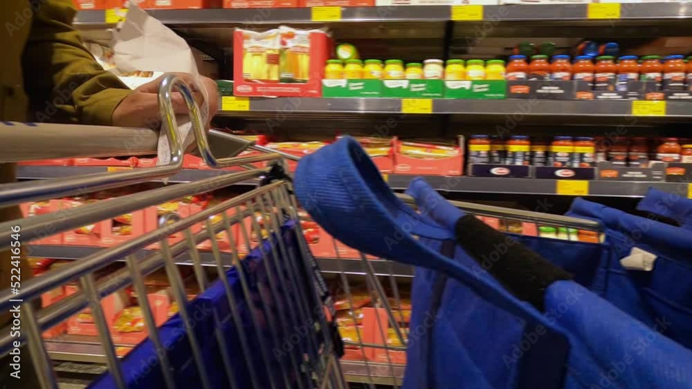 Tracking shot of a shopping cart being pushed while holding a shopping list. Close up.