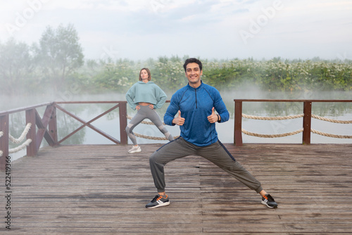 Young sporty couple training on wooden platform on the foggy river at the morning time. Healthy lifestyle concept  © Vitaliy