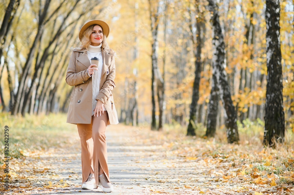 Pretty young woman with coffee cup in the autumn park Pretty young woman with coffee cup in the autumn park