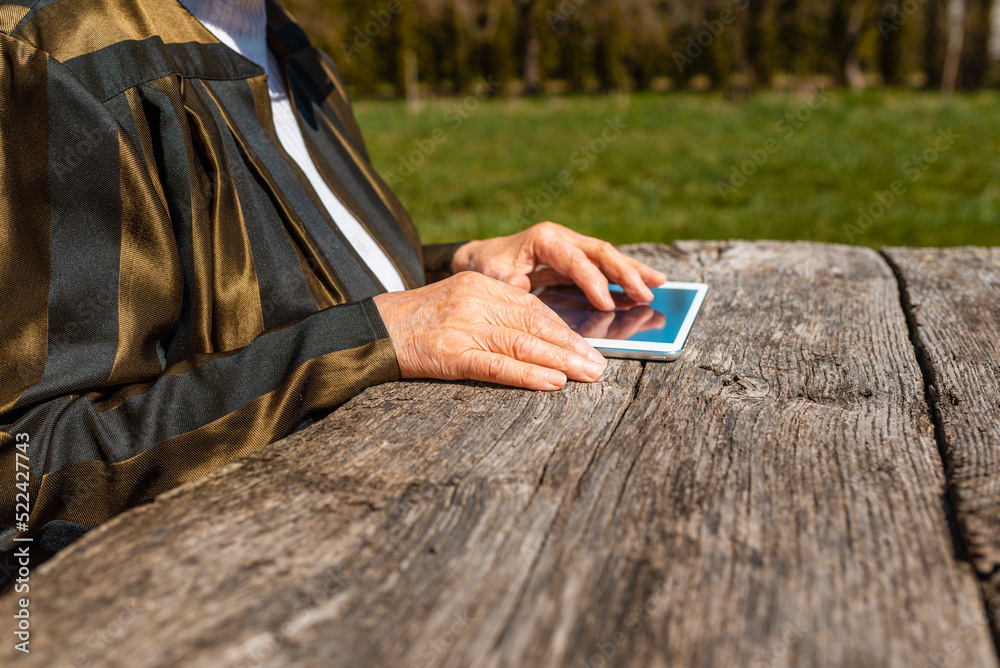 Hands of senior woman holding tablet PC, outdoors in warm summer day.Close up.Selective focus.