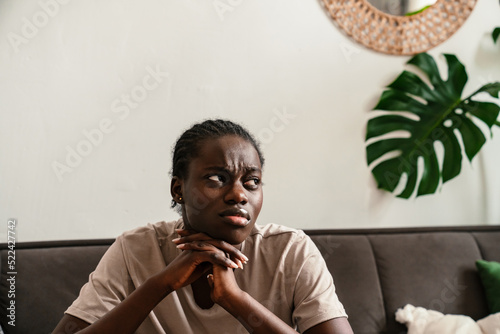 African american woman expressing sadness while sitting on sofa