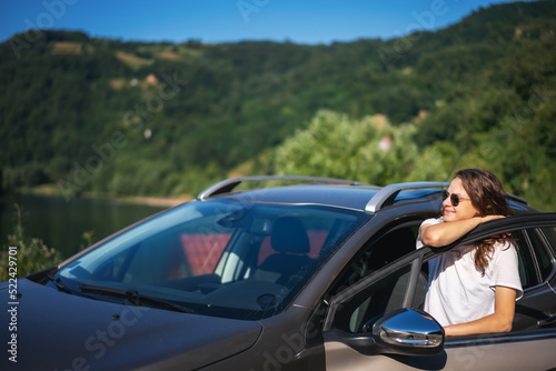 Young beautiful happy woman driver traveling countryside by car