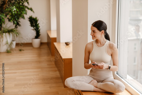 Young white woman using mobile phone during yoga practice