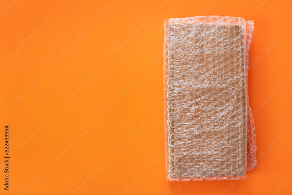 Obraz premium Bubbles covering the box by bubble wrap for protection product cracked on a orange background