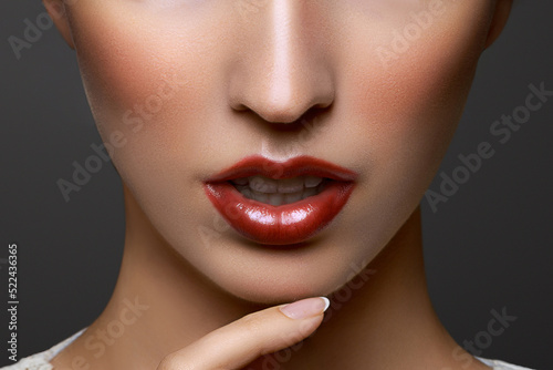 Close-up portrait of beautiful young woman lips with bright red lipstick