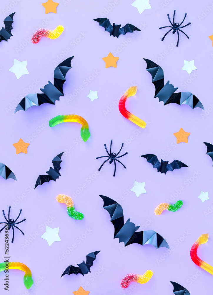 pattern composition on the theme of the holiday halloween sweets bats spiders on a purple background