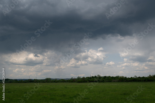 Gloomy cloud with rain over grassland, rainy day in field