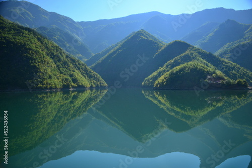Albania, Lake Koman is a reservoir on the Drin River in northern Albania, surrounded by dense forested hills, vertical slopes, deep gorges and a narrow valley