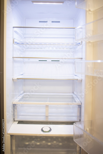 Clean empty refrigerator after thorough cleaning cleaning service or housewife. White transparent shelves and refrigerator door. Concept: cleaning, cleaning service, home routine. Kitchen appliances