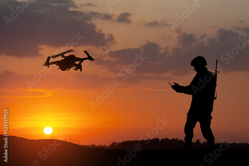 Silhouettes of soldiers are using drone and laptop computer for scouting during military operation.