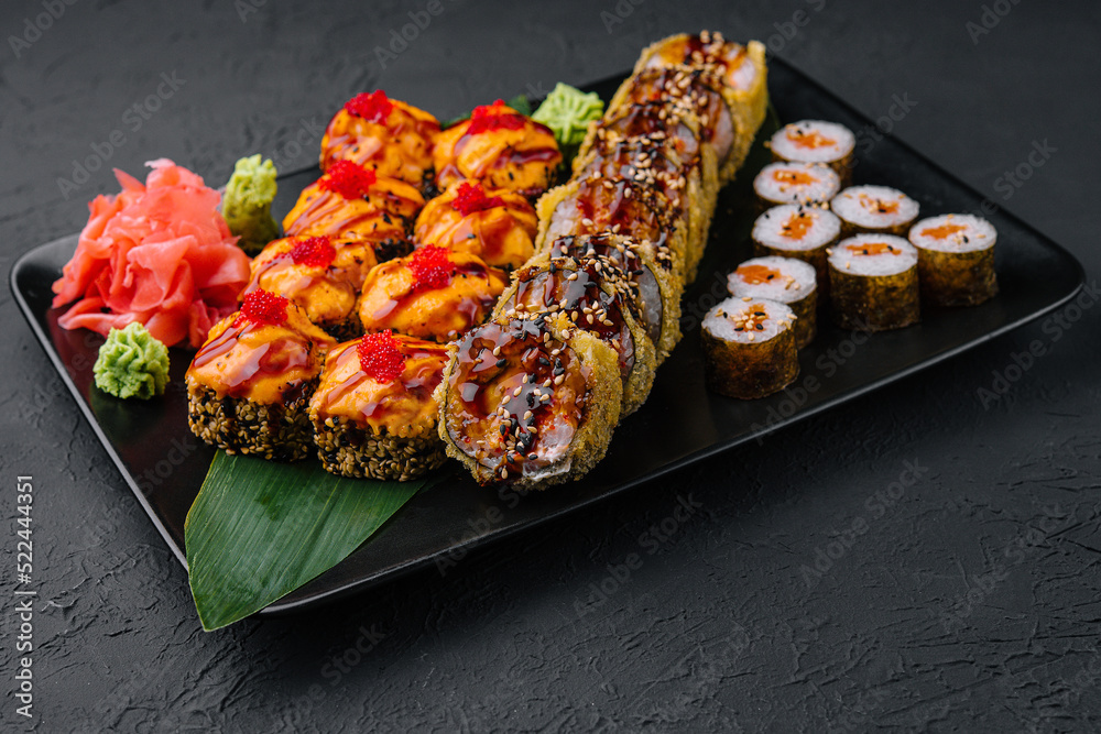 Served warm sushi with ginger and wasabi on a black stone plate Served warm sushi with ginger and wasabi on a black stone plate