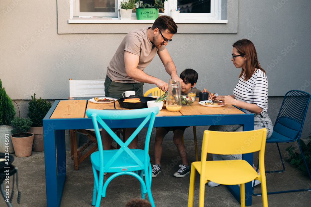 family eating lunch together in backyard of their home family eating lunch together in backyard of their home