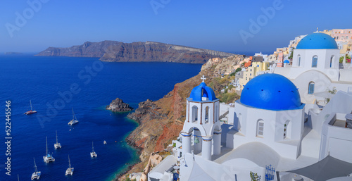 Santorini, Greece. Lovely view of Oia village with traditional famous blue domed church on the Caldera in the Aegean Sea. Traditional Cycladic architecture in white and blue.
