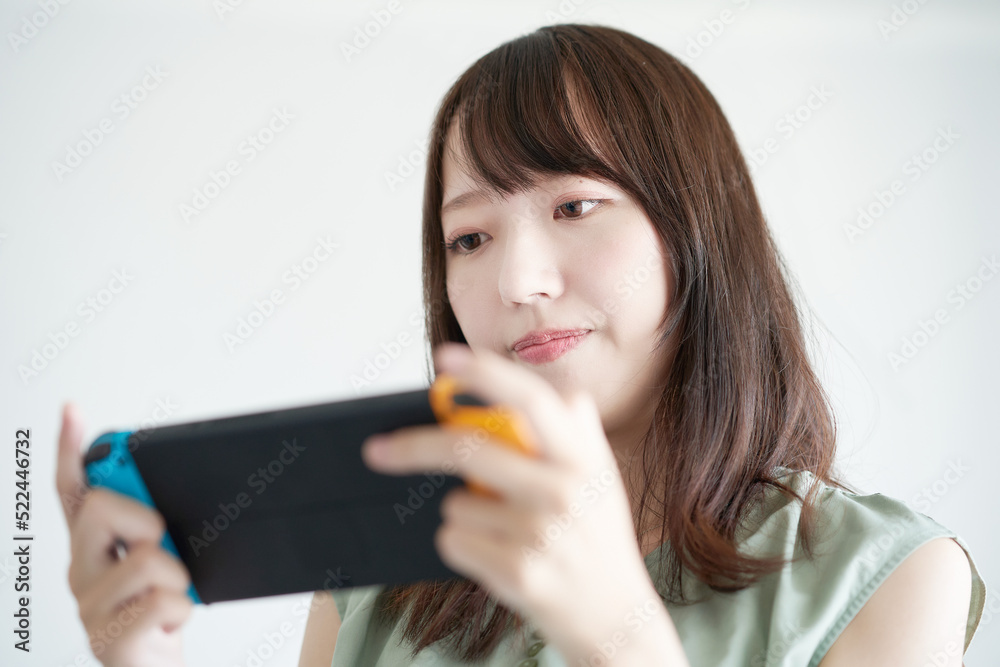 携帯型のゲーム機で遊ぶ女性