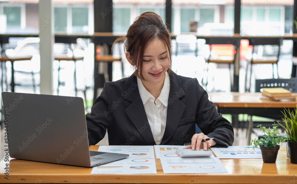 Marketing, Financial, Accounting, Planning, Business women analyze company results and profits with graph statistics. Use a laptop computer and a calculator to calculate the company's balance. Marketing, Financial, Accounting, Planning, Business women analyze company results and profits with graph statistics. Use a laptop computer and a calculator to calculate the company's balance.