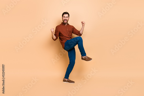 Full length photo of delighted astonished person raise fists success luck isolated on beige color background