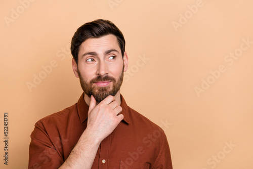 Photo of minded creative person hand touch chin look interested empty space isolated on beige color background