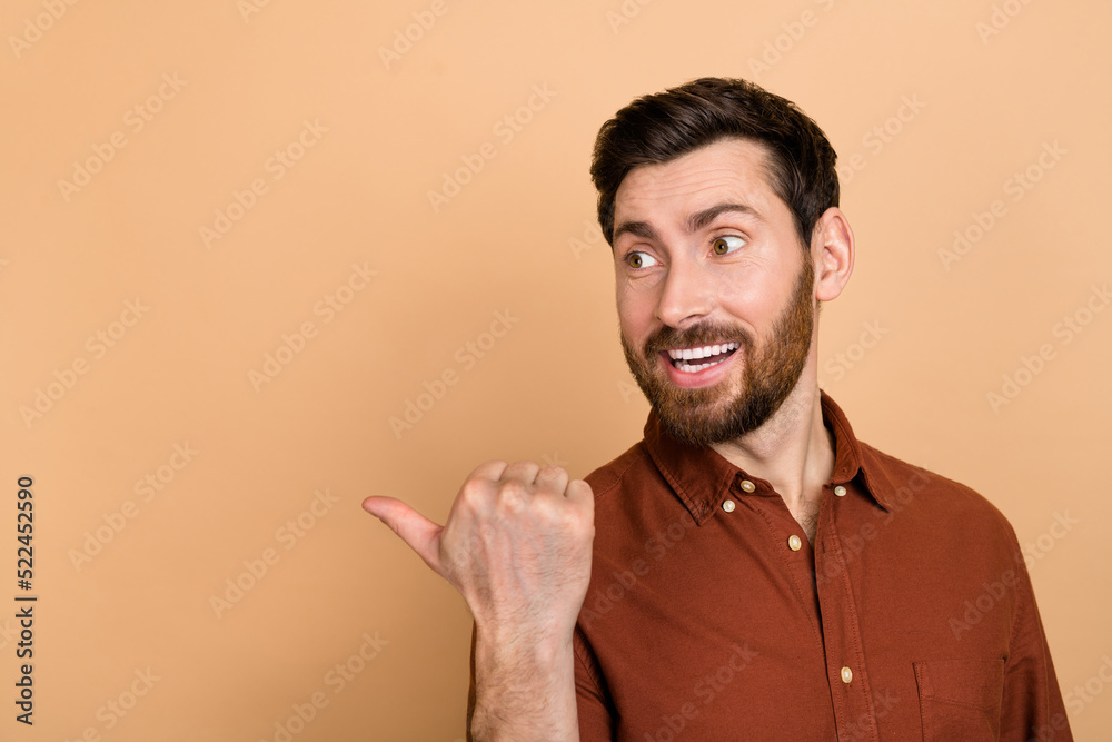 Photo of positive cheerful man look indicate finger empty space blank isolated on beige color background Photo of positive cheerful man look indicate finger empty space blank isolated on beige color background