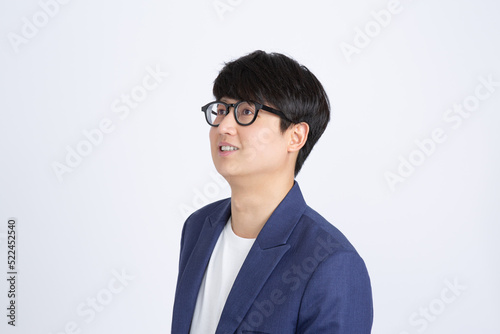 Positive handsome Asian business man smiling and looking up aside isolated white background