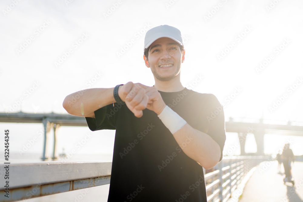 Uses a fitness watch and a tracker bracelet on his arm, a male runner athlete running does a workout.