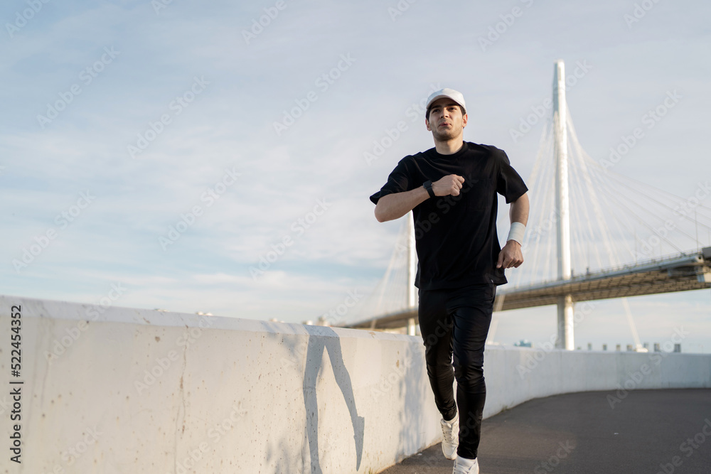 Runner male athlete running does a workout exercise in the city, uses a fitness watch Runner male athlete running does a workout exercise in the city, uses a fitness watch