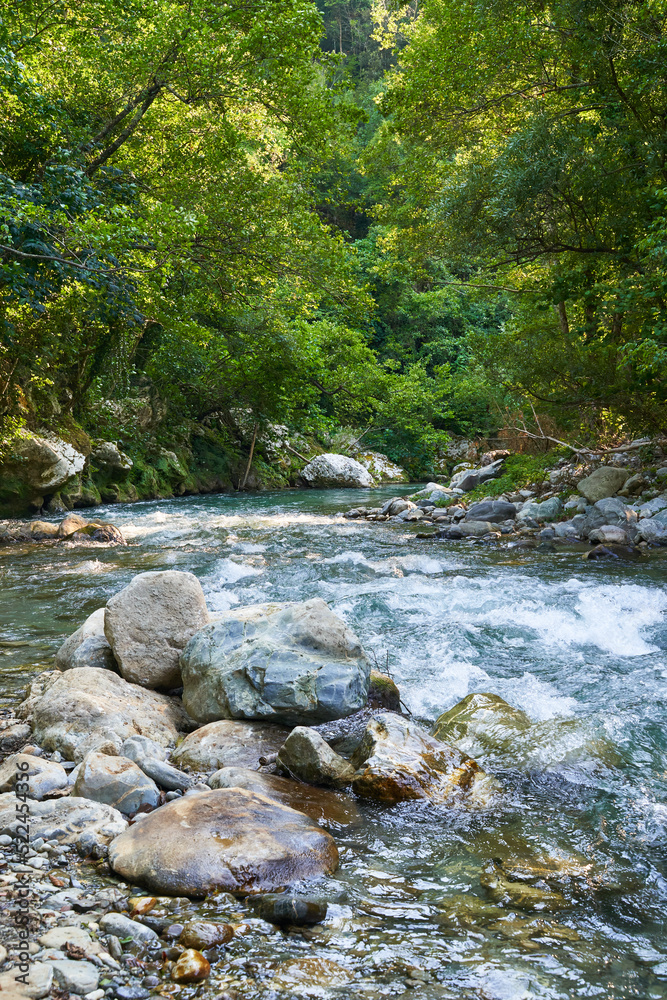 The Lao River flows through Calabria and Basilicata, Italy. It is part of the Pollino nature reserve which has been recognized by Unesco. There are also canyons there. River with stones in foreground. The Lao River flows through Calabria and Basilicata, Italy. It is part of the Pollino nature reserve which has been recognized by Unesco. There are also canyons there. River with stones in foreground.