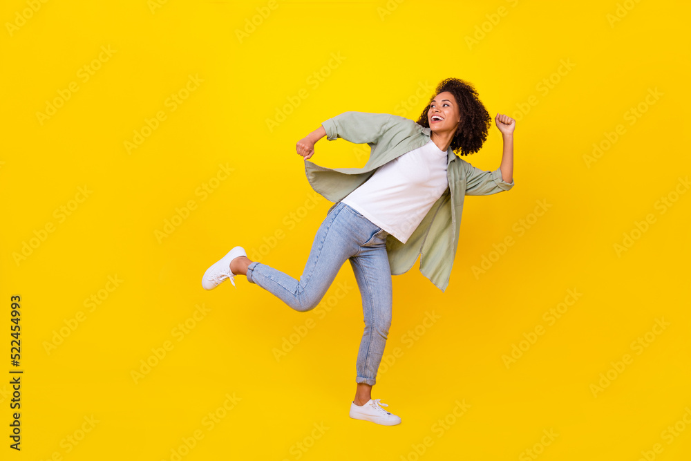 Full length photo of charming young girl wavy hair running look empty space dressed stylish khaki shirt isolated on yellow color background