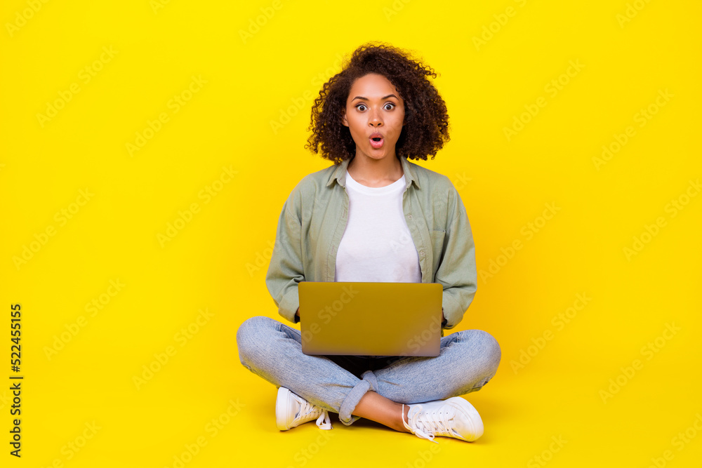 Naklejka premium Full body photo of attractive young girl wavy hair impressed netbook fast wifi wear stylish khaki look isolated on yellow color background