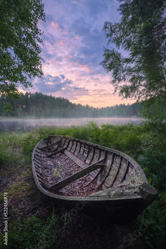 Beautiful sunrise in tranquil lake at summer evening in Finland with wooden boat