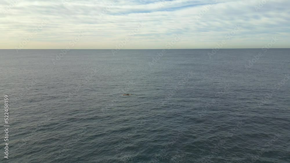 Single fishing kayak paddling across the ocean with beautiful horizon at the open sea. Aerial view. Single fishing kayak paddling across the ocean with beautiful horizon at the open sea. Aerial view.