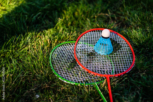 Close-up of two badminton racquets and a shuttlecock on the grass in summer photo
