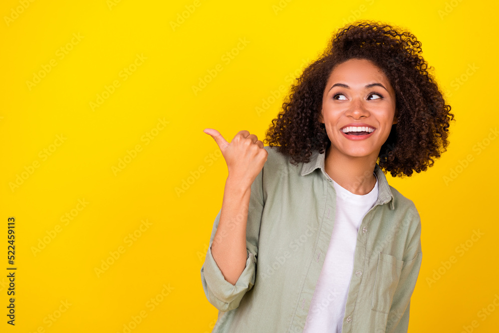 Photo of funky curly millennial lady look index empty space wear grey shirt isolated on yellow color background Photo of funky curly millennial lady look index empty space wear grey shirt isolated on yellow color background