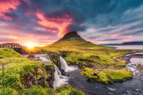 Landscape of sunset over Kirkjufell mountain with Kirkjufellsfoss waterfall and colorful pileus cloud on summer at Iceland