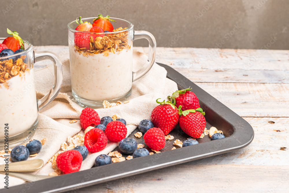 Granola with nuts, yogurt and red fruits berries in a jar. Breakfast parfait with muesli, yoghurt, red fruits berries and honey, white kitchen background. Granola with nuts, yogurt and red fruits berries in a jar. Breakfast parfait with muesli, yoghurt, red fruits berries and honey, white kitchen background.